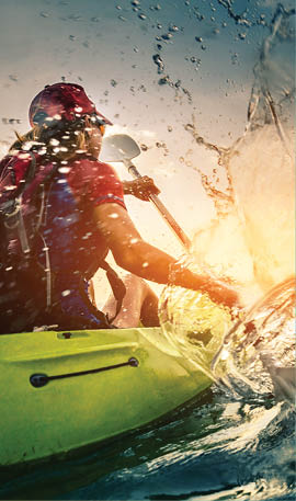 Young lady paddling hard the kayak with lots of splashes