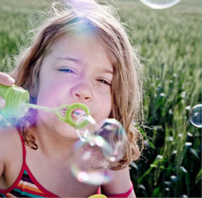 Girl blowing bubbles to camera